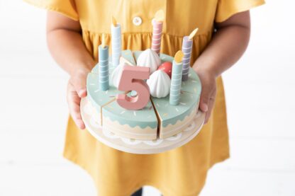 Dziecko trzyma w rękach drewniany tort urodzinowy, marki Little Dutch.